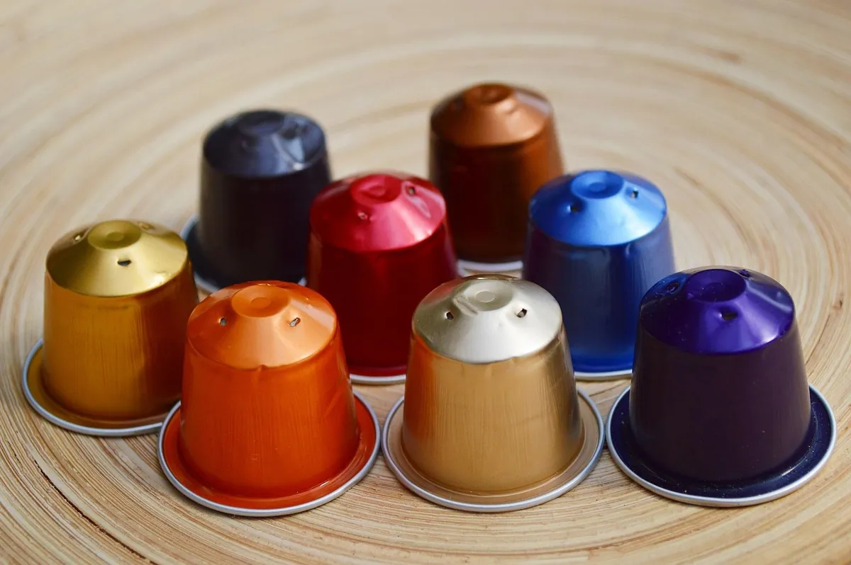Cápsulas de café Nespresso en varios colores sobre base de madera — variedad del sistema de cápsulas compatible