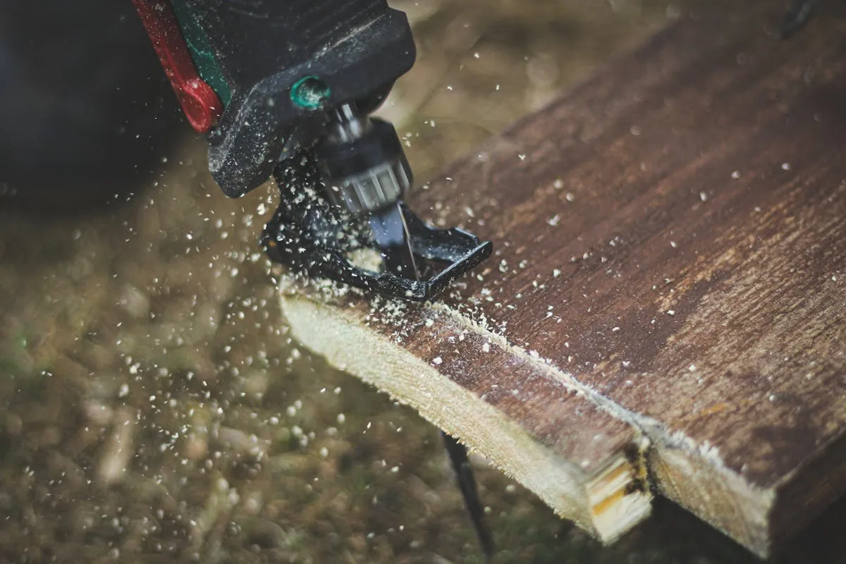 Hoja de sierra caladora cortando madera con aserrín visible — corte de precisión en tablero