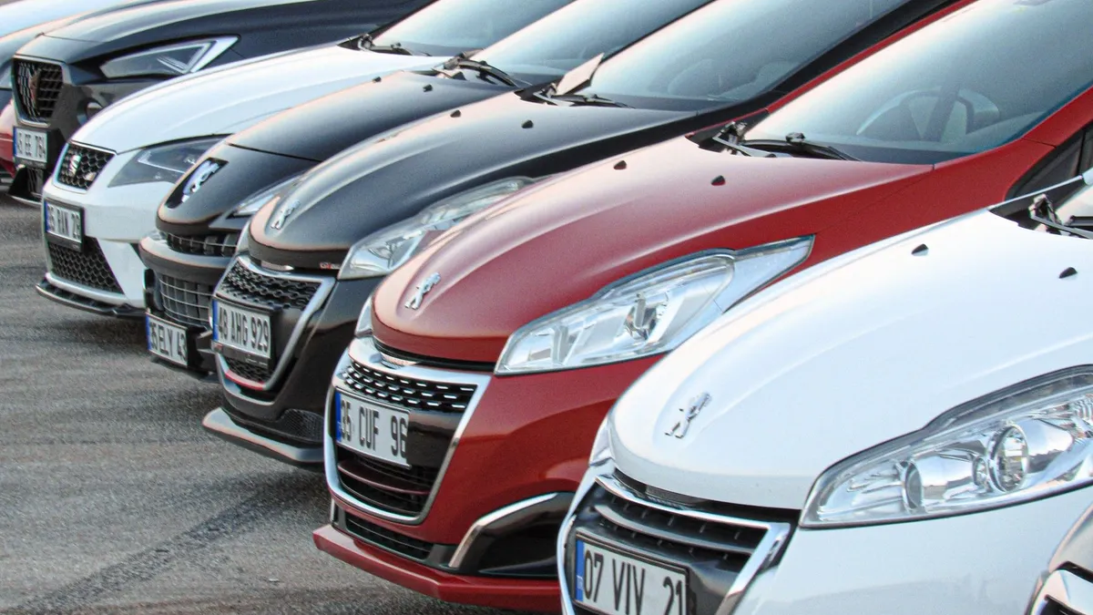Fila de carros de cores diferentes estacionados em um pátio de loja.