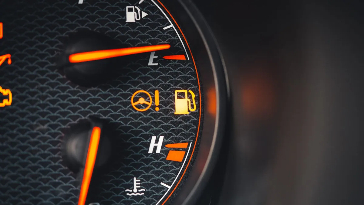 Detalhe de painel de carro com indicadores de combustível, temperatura e luzes acesas.