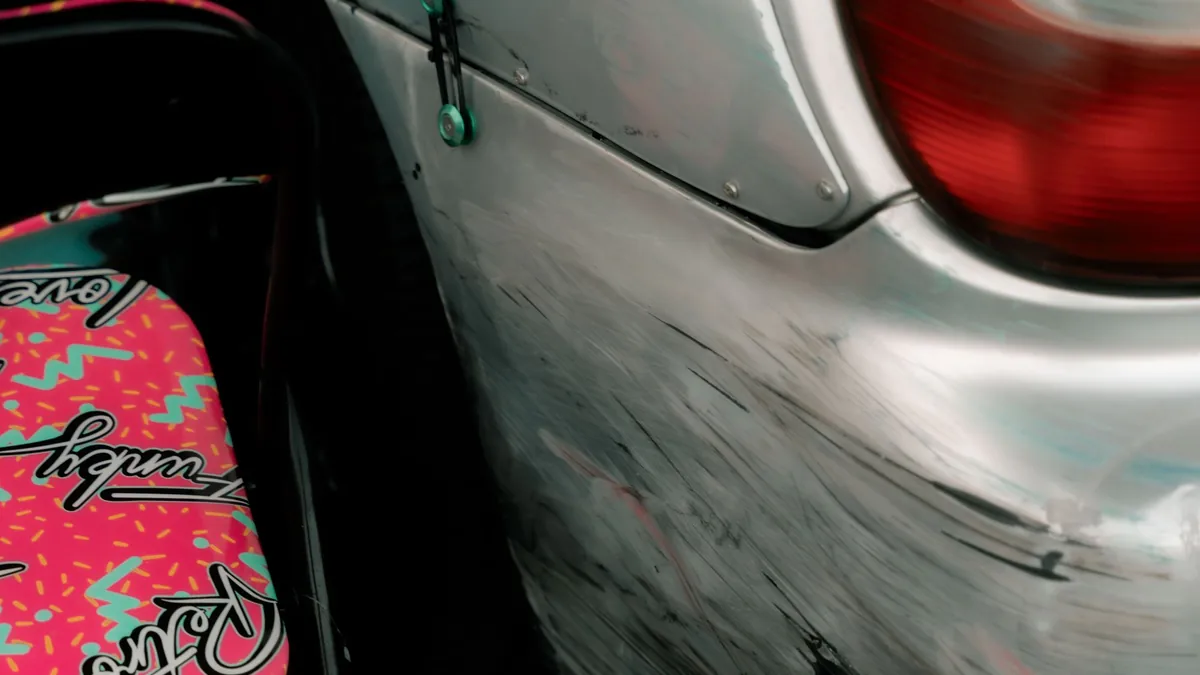 Detalhe de para-choque prateado com riscos e marcas na pintura.
